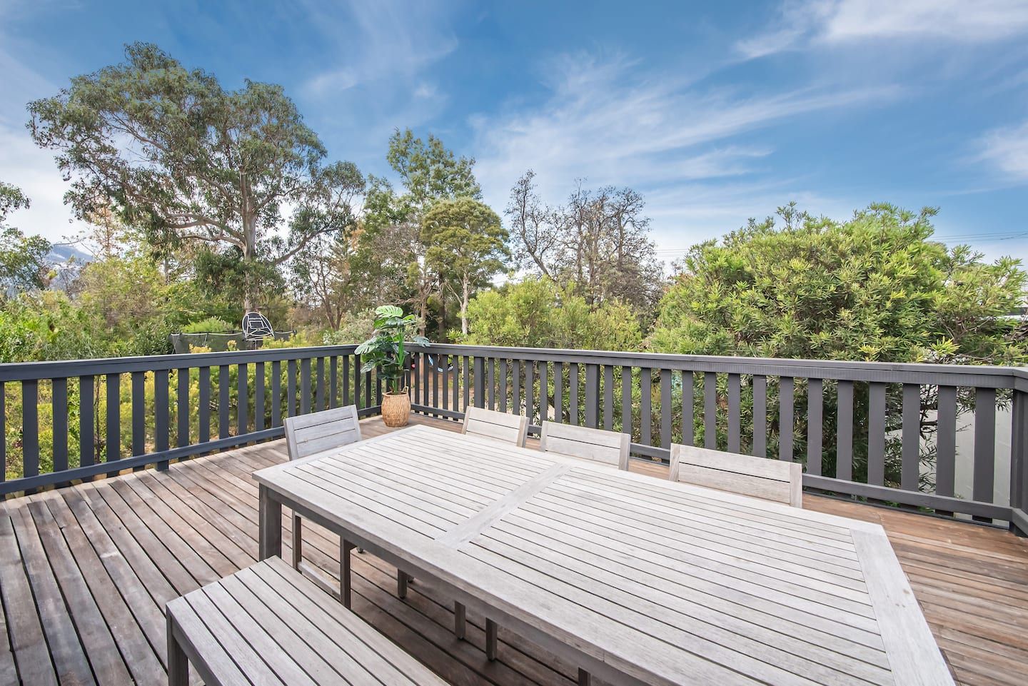 The deck with a long outdoor table, among the gum trees