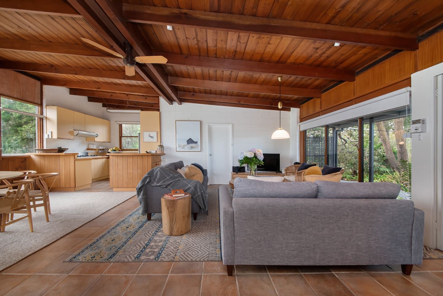 The open living room, lined in timber, with the dining area beyond