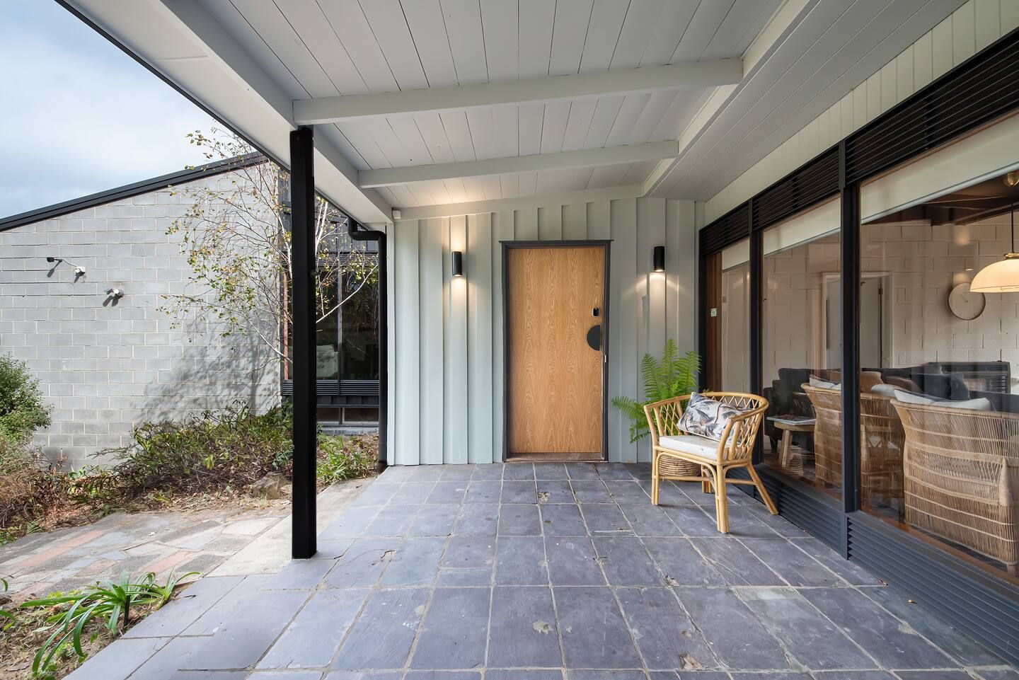The front porch of Somers Dunescape, with a timber front door and a cane chair