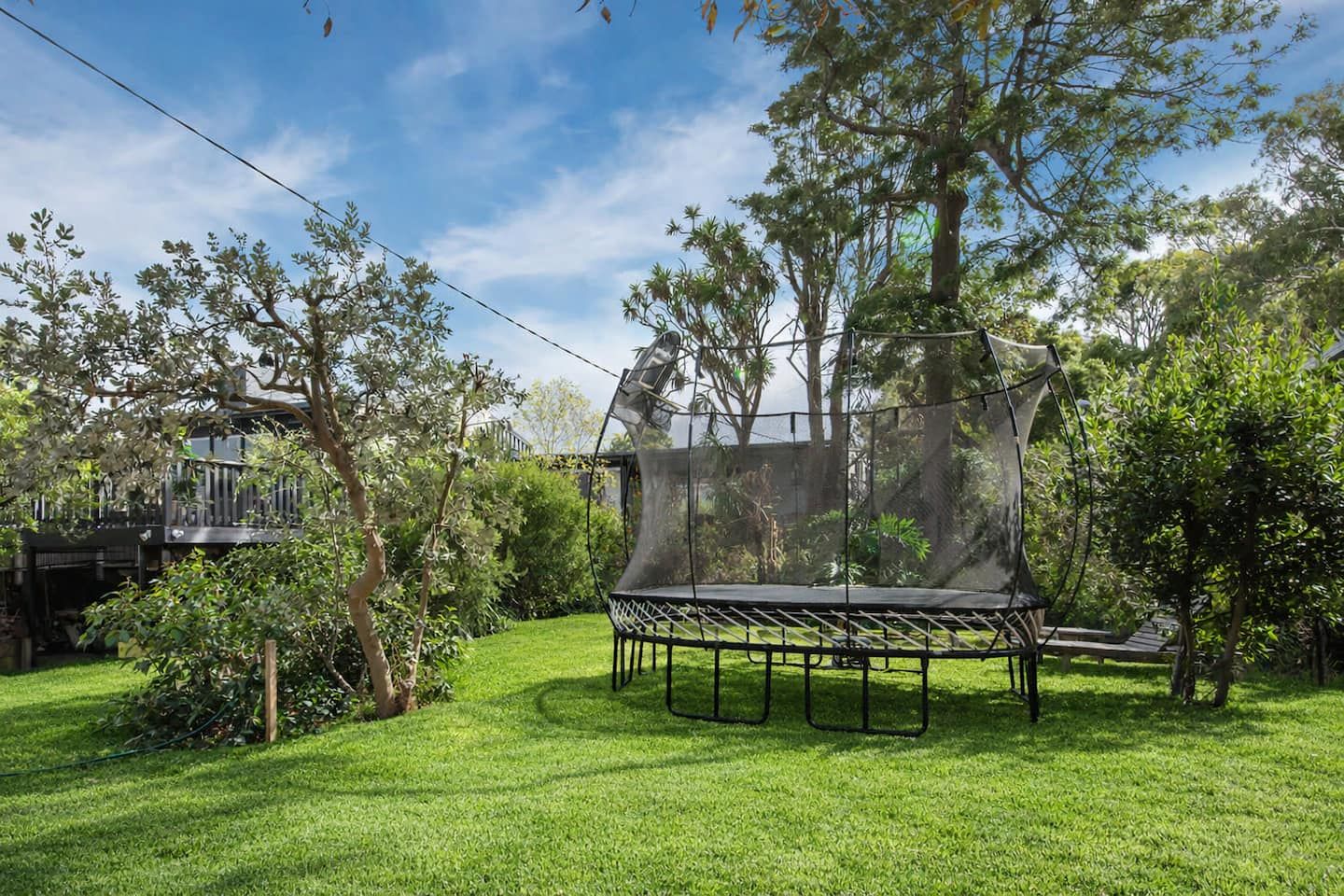 The fenced backyard with a Springfree trampoline on the lawn